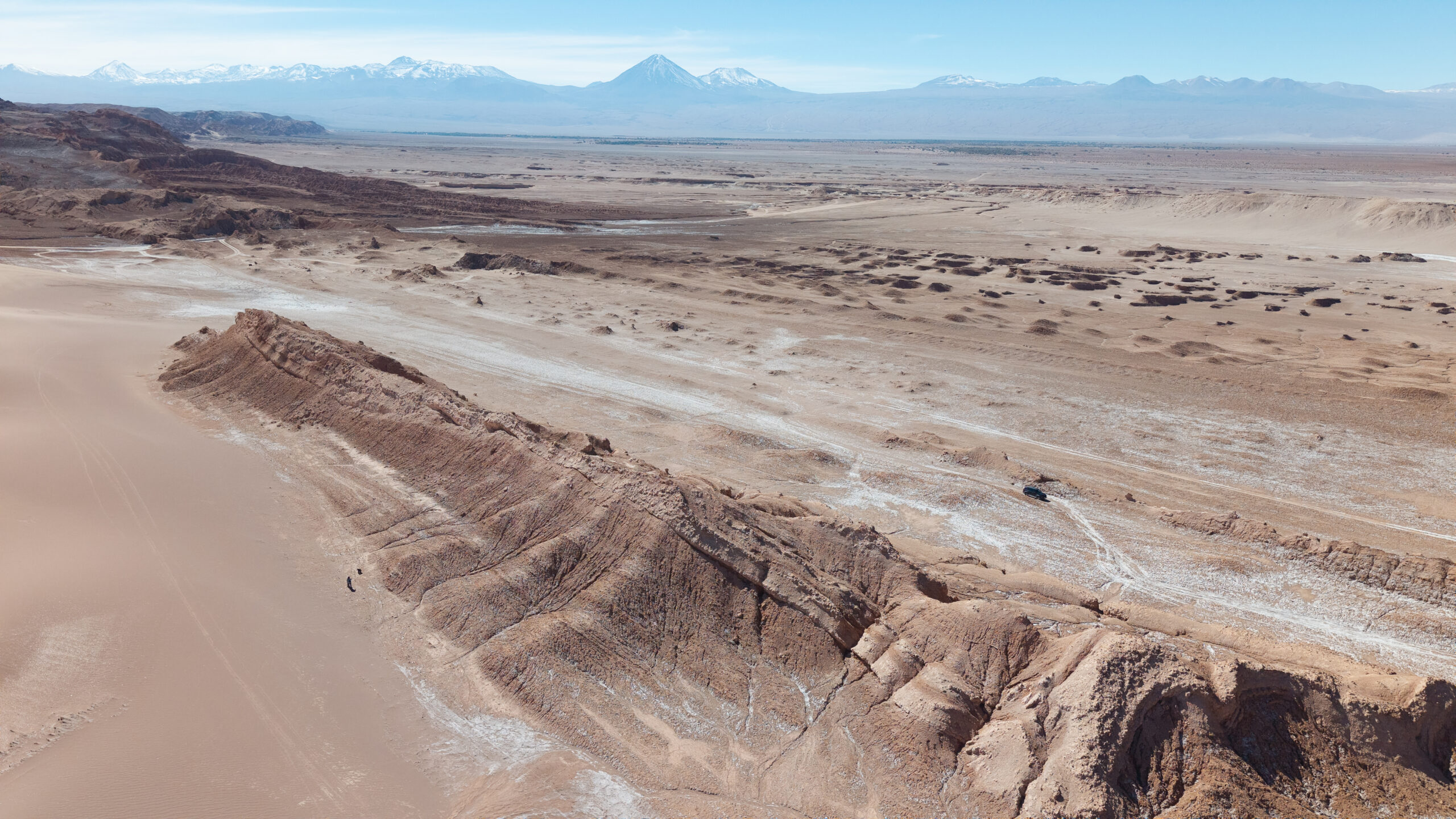 paisaje de la cordillera de la sal con grandes formaciones rocosas en primer plano y la cadena de volcanes en el horizonte.