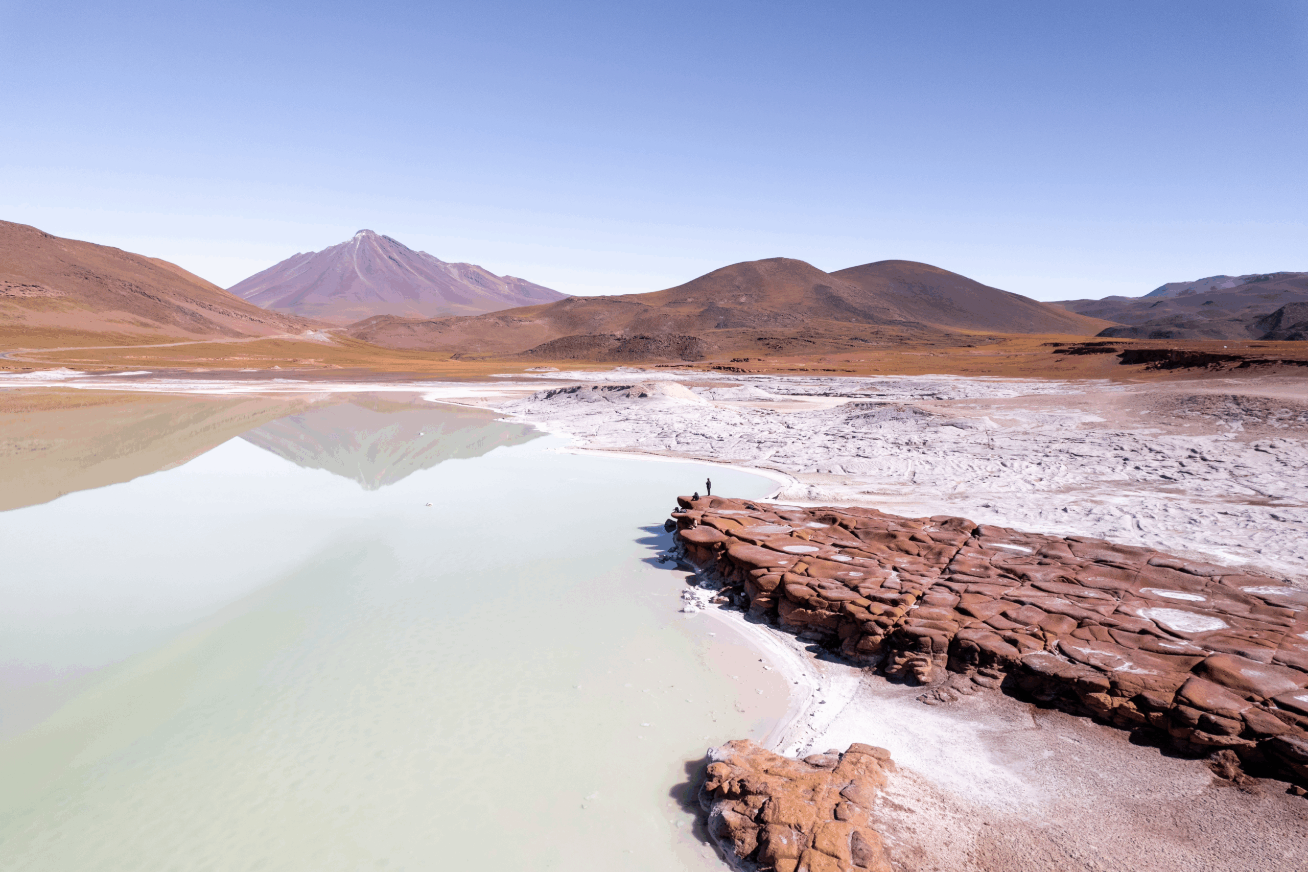 Paisaje de una laguna con volcanes de fondo y las características formaciones rocosas de piedras rojas en san pedro de atacama.