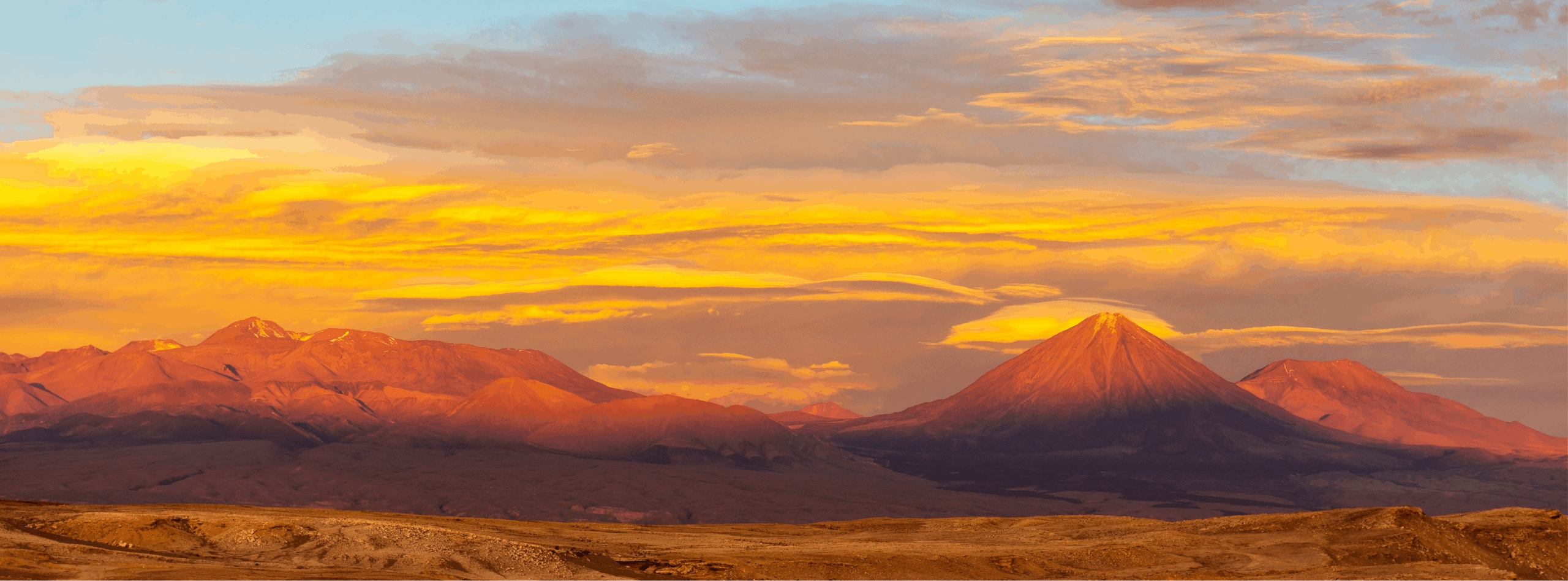 hermosa imagen del volcán licancabur bañado en tonos anaranjados y con nubes amarillas debido a la luz del atardecer.